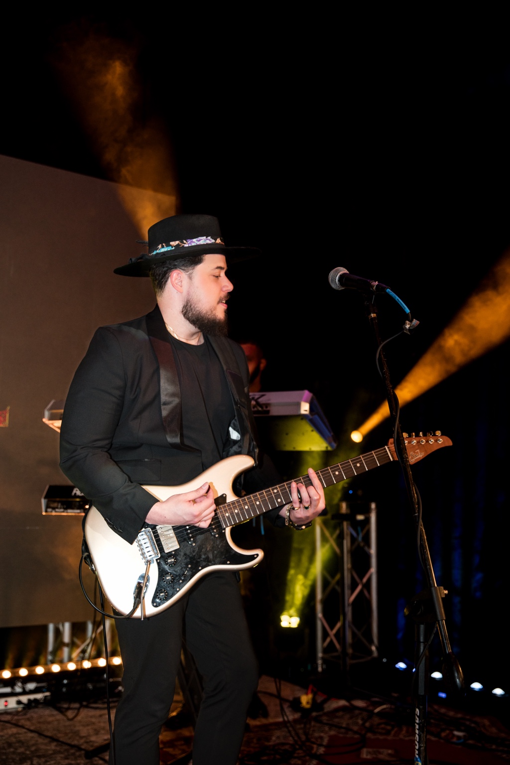 Will playing his cream-colored Suhr guitar against gold stage lighting